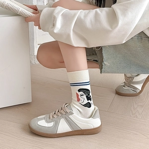 Detailed shot of calf socks with abstract face print and retro trainer shoes on wood floor