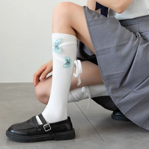 Detail of white Lolita knee-high socks with blue butterfly appliques and lace-up ribbons