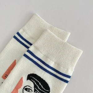 Detail of ribbed cuff and abstract face illustration on mid-calf crew athletic socks