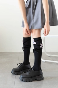 Detail of Lolita style knee-high socks featuring pink butterfly embroidery and ribbon lace-up