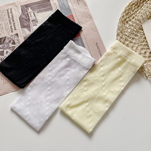Detailed view of white, yellow, and black sheer socks with polka dots on vintage newspaper