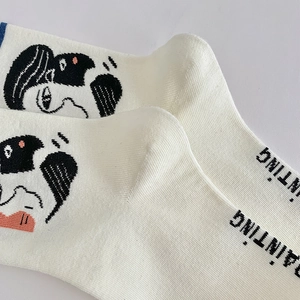 Close-up of knit crew socks in beige with black artistic portrait and PAINTING text