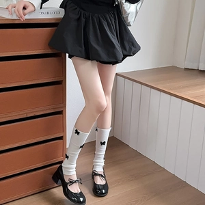 Detail of white ribbed leg warmers with black 3D bows paired with Mary Jane shoes