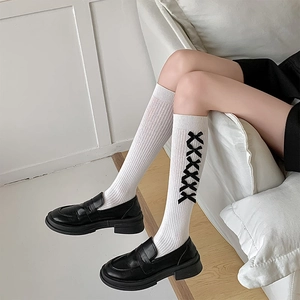 Close-up of white knee-high socks with black ribbon lace-up and ribbed texture detail