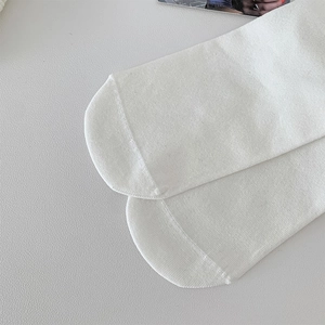 Close-up of white cotton crew socks showing flat-toe seam and fine knit texture details