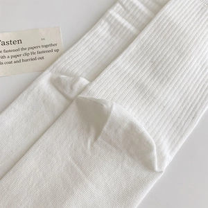 Close-up of cream white ribbed knit texture and heel stitching on cotton socks