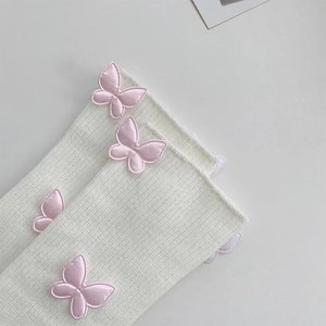 Detail of white ribbed leg warmers with pink 3D satin bow embroidery and cotton texture