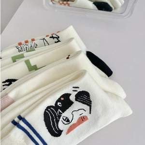 Close-up of white cotton socks with artistic hand-drawn cat and figure illustrations