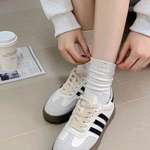 Close-up of stylish white polka dot socks paired with retro striped sneakers on a plain floor
