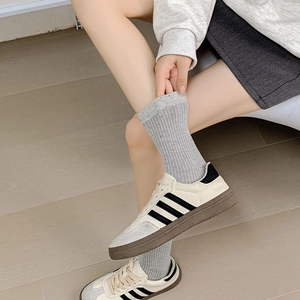 Close-up of grey ribbed mid-calf socks paired with retro striped leather sneakers