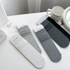 Set of four cotton socks in white, grey and black with ribbed texture and paper tags