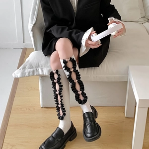 Detailed view of white Lolita knee-high socks with black ruffles and heart accents