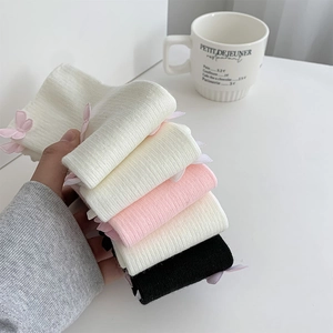 Close-up of knit leg warmers with ribbon bows and ribbed texture in sweet ballet style