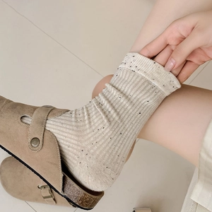 Detail of oatmeal ribbed socks with black dots paired with brown suede sandals