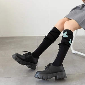 Detail of black knee-high socks with blue butterfly embroidery and lace-up velvet ribbons
