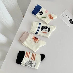 Flat lay of artistic crew socks with abstract hand-drawn prints and minimalist motifs