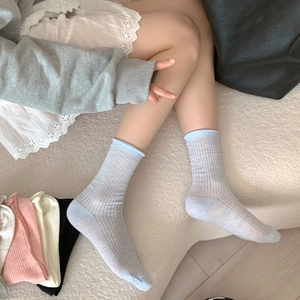 Détail de chaussettes légères à côtes en bleu, rose et beige aux tons pastel doux