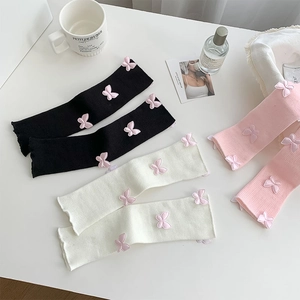 Detail of ruffled knit leg warmers with mesh bow in black, white and pink colors