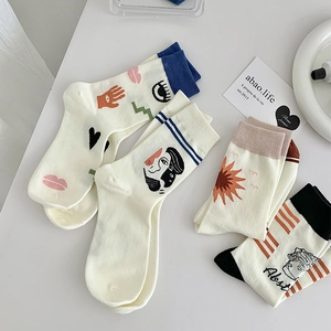 Artistic mid-calf socks with abstract face, lips, and sun embroidery patterns on white cotton