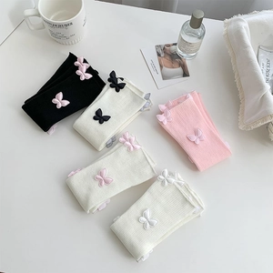 Flat lay of ribbed leg warmers with 3D butterfly embroidery in assorted soft colors