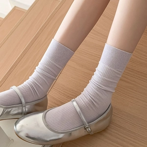 White ribbed cotton crew socks paired with silver Mary Jane shoes on a wooden staircase