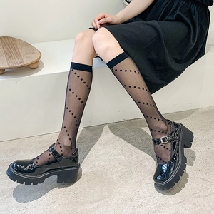 Close-up of black polka dot mesh socks paired with shiny patent leather platform shoes
