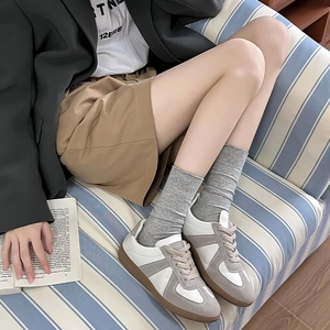 On-foot look of vintage GAT sneakers featuring grey suede and white leather stitching