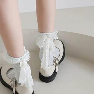 Détail de chaussettes en résille blanches avec nœud en dentelle et chaussures Mary Jane