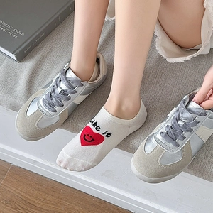 Detail of silver grey sneakers with satin laces and heart pattern low cut socks