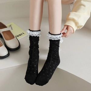 Détail de chaussettes noires avec dentelle blanche double couche et motif à pois