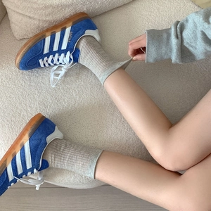 Détail de chaussettes grises en coton côtelé avec des baskets rétro en daim bleu