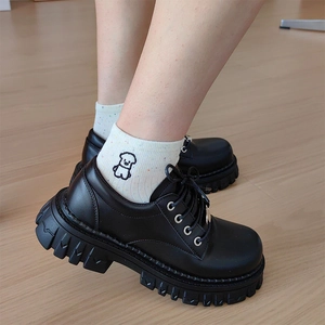 Close-up of black platform derby shoes with lug sole and cute embroidered socks