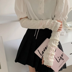 Lolita style cream knit arm warmers featuring pink ribbon bows and cable stitch texture