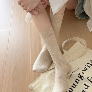 Detailed close-up of beige ribbed crew socks on model with Japanese minimalist style