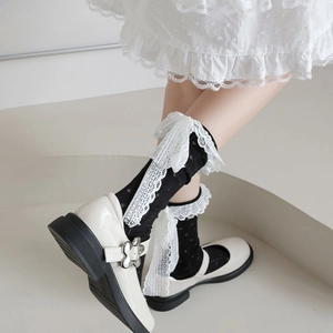 Détail de chaussettes noires à pois avec nœuds en dentelle blanche et Mary Janes