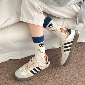 Detail of artistic eye-patterned mid-calf socks with blue ribbed cuffs and casual shoes