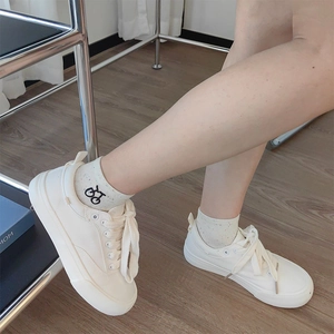 Close-up of white canvas sneakers and socks with colorful dots and bicycle embroidery