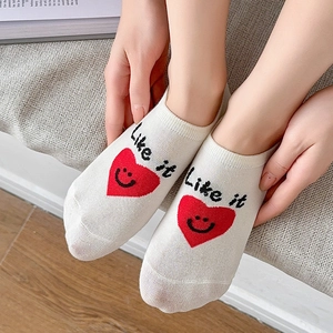 Detail of white cotton low cut socks featuring red heart smile and Like It text embroidery