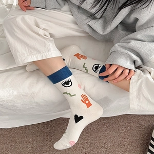 Detail of artistic cotton socks with hand-drawn eyes and hearts patterns on mid-calf length