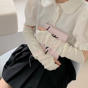 Detail of knit arm warmers featuring pink ribbon bows and delicate cross-tie design
