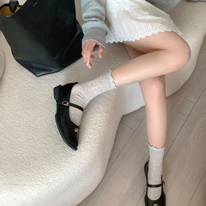 Dettaglio calzini a rete bianchi con bordo a balze e scarpe Mary Jane nere eleganti