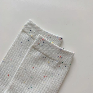 Macro shot of white ribbed knit socks with colorful confetti specks and elastic cuffs