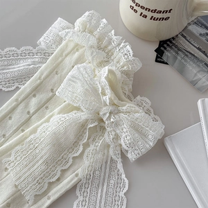 Détail de chaussettes en dentelle crème avec nœud élégant et motifs ajourés aérés