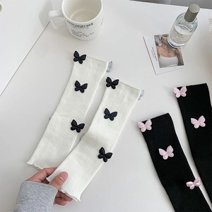 Detail of knit leg warmers with 3D butterfly appliques and rib-knit texture