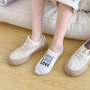 Detail of white low-cut invisible socks with black LOVE text and retro canvas shoes