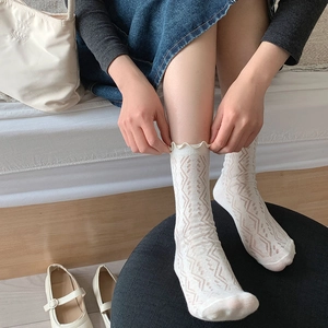 Dettaglio calzini in maglia bianco crema con motivi a onde ed eleganti bordi a balze