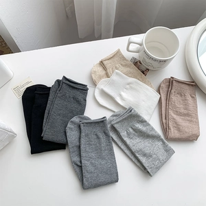 Flat lay of colorful ribbed mid-calf socks in various neutral tones on a white table