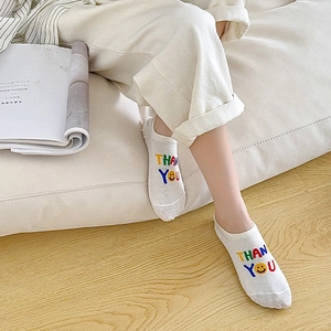 Detail of white cotton low-cut socks with embroidered Thank You lettering and smiley