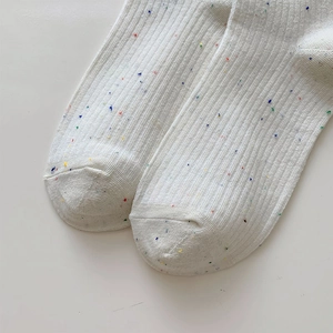 Close-up of white ribbed knit socks with colorful rainbow dot patterns and soft texture