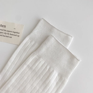 Detail of white vertical ribbed crew socks featuring high-elastic cuffs and fine texture